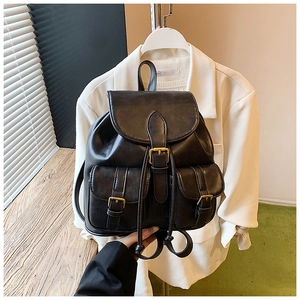 Detalle de mochila de cuero negro mate con hebillas metálicas vintage y dos bolsillos frontales