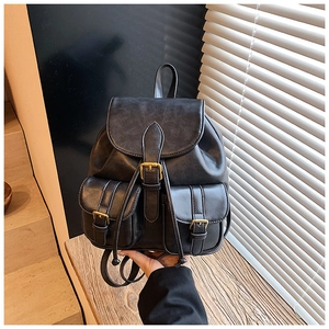 Detalle de mini mochila vintage de cuero negro con hebillas y cierre de cordón