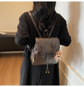 Detail of vintage brown PU leather backpack with decorative straps and plush dog charm