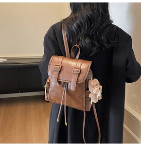 Detail view of brown PU leather backpack with drawstring closure and decorative belt straps