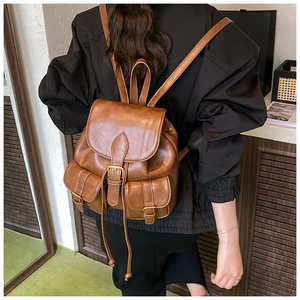 Detalle de mochila de cuero marrón con hebillas metálicas y bolsillos de solapa