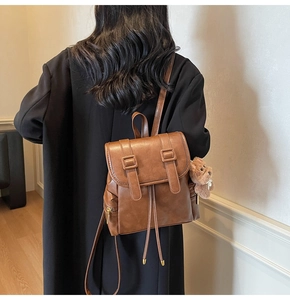 Detail of vintage brown leather backpack with drawstring and plush bear charm