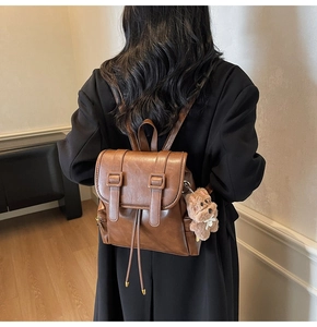 Detail of dark brown leather backpack with drawstring closure and cute dog charm
