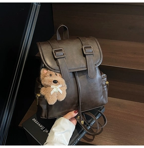 Close-up of retro brown faux leather backpack with drawstring closure and teddy bear charm