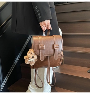 Detail of vintage brown leather backpack with strap buckles and plush bear accessory