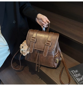 Close-up of vintage brown leather backpack with magnetic buckles and plush bear charm