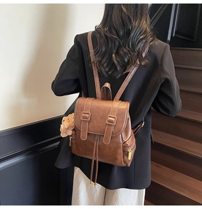 Detail view of brown PU leather backpack with vintage texture and plush bear pendant