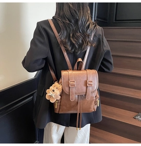 Detail of vintage brown leather backpack with drawstring closure and teddy bear charm