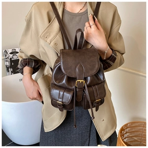 Detalle de mochila vintage de cuero marrón con hebillas doradas y bolsillos frontales