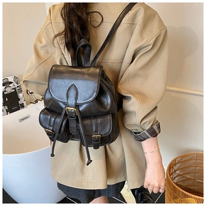 Close-up of black vintage leather backpack with dual front pockets and drawstring detail