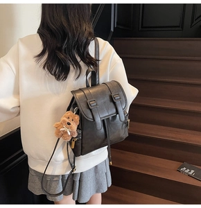 Close-up of vintage brown faux leather backpack with gold zippers and a plush bear charm