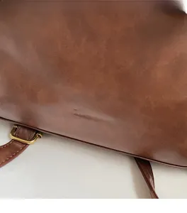 Detail of dark brown leather backpack with embossed logo and golden metal buckle