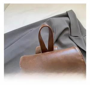 Detail of brown leather backpack with neat white stitching and sturdy top handle