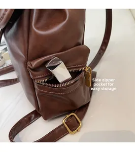 Close-up of brown vintage leather backpack showing side zipper pocket for storage