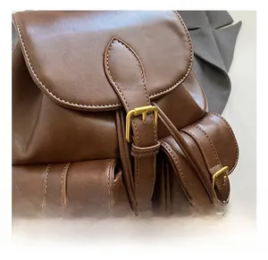Close-up of high-quality gold buckles and matte brown faux leather texture on the backpack