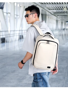 Cream white expandable laptop backpack worn by man in a modern airport terminal setting