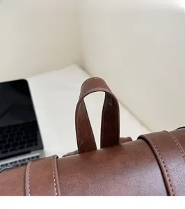 Detail view of reinforced handle and premium lychee grain texture on dark brown backpack