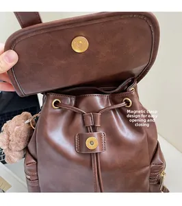 Detail of brown leather backpack featuring a secure magnetic buckle and drawstring closure