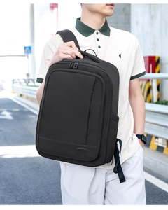 Side view of black expandable commuter backpack worn by male model on city street