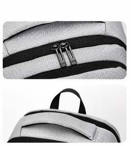 Detalle de cremalleras dobles y asa superior reforzada en bolso de pecho gris oxford