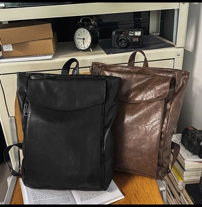 Détail de sacs à dos en cuir rétro noirs et marron foncé posés sur un siège en bois