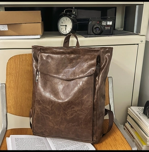 Gros plan d'un sac à dos vintage en cuir PU marron avec texture sur chaise en bois