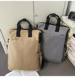 Détail des sacs à dos en toile kaki et gris avec poignées renforcées et poches latérales