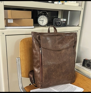 Vue détaillée de la poche avant incurvée et de la texture cuir ciré du sac à dos rétro marron
