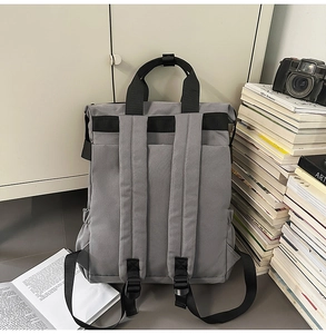 Détails du sac à dos gris montrant les bretelles noires rembourrées et les poches latérales