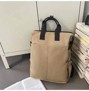 Détail d'un sac à dos en toile kaki avec poches utilitaires sur un fond minimaliste épuré
