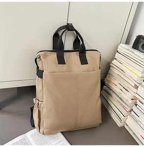 Gros plan d'un sac à dos en toile kaki avec poches frontales et poignées noires