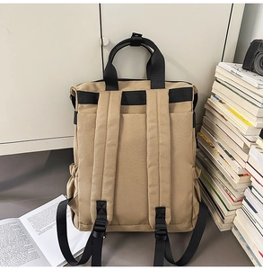 Détail du sac à dos en toile kaki avec des larges bretelles noires dans un bureau