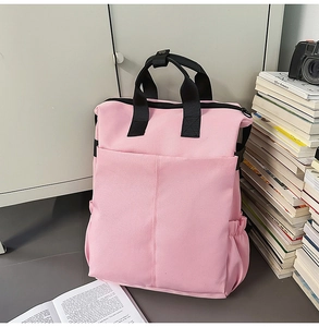 Détail latéral du sac à dos en toile rose avec poignée noire et poche latérale élastique