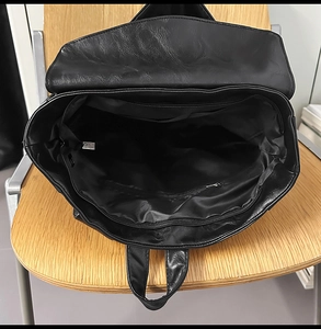 Vue intérieure du sac à dos en similicuir noir montrant le compartiment et la poche zippée