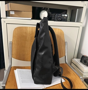 Vue latérale du sac à dos en cuir noir montrant l'épaisseur et les bretelles en mesh