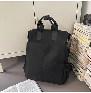 Vue détaillée du sac à dos en toile noire avec grandes poches avant et boucles métalliques