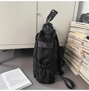 Détail latéral d'un sac à dos noir en nylon avec poches élastiques et fermetures à anneaux
