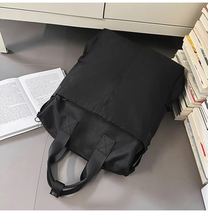 Gros plan détaillé d'un sac à dos polyvalent en nylon noir posé sur un sol gris