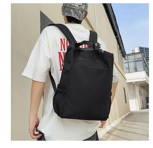 Détail du sac à dos de voyage noir avec poignées renforcées et poche latérale à cordon serré