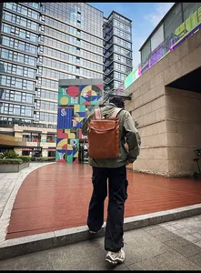 Vue arrière d'un mannequin portant un sac à dos en cuir marron vintage en milieu urbain
