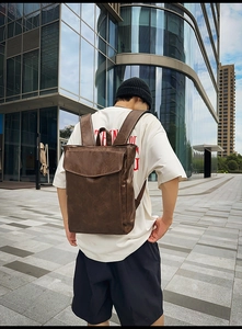 Photo en extérieur d'un sac à dos en cuir marron vintage porté par un mannequin en ville