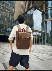 Photo de mode d'un sac à dos vintage en cuir marron foncé porté dans un décor urbain