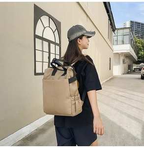 Vue latérale d'un grand sac à dos en toile kaki avec doubles poignées et poches latérales