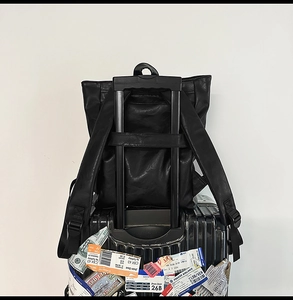 Détail du sac à dos en cuir noir avec sangle arrière pour fixation sur valise