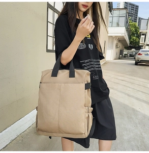Vue détaillée du sac à dos en toile kaki avec des sangles noires et des poches latérales