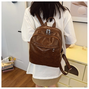 Close-up of vintage brown leather backpack with multi-pocket design on female model