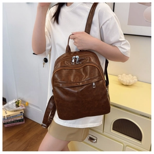 Close-up of vintage brown oil-wax leather backpack with silver zippers and multi-pocket detail