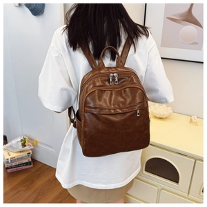 Detail of dark brown vintage faux leather backpack with silver zippers and multi-pocket layout