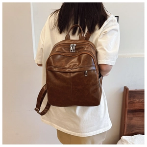 Close-up of a dark brown PU leather backpack featuring multi-pocket storage and metal zippers