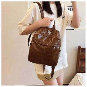 Detail of brown faux leather backpack with multi-pocket design on casual model